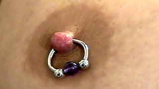 Busty slut poses while piercing her tits